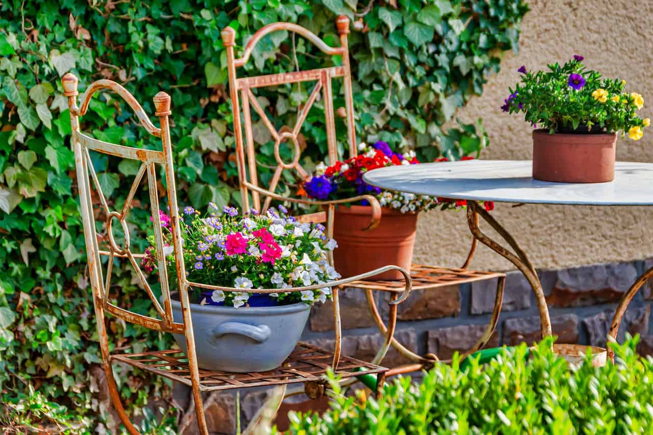 Gartengestaltung mit alten Stühlen und Blumenschalen